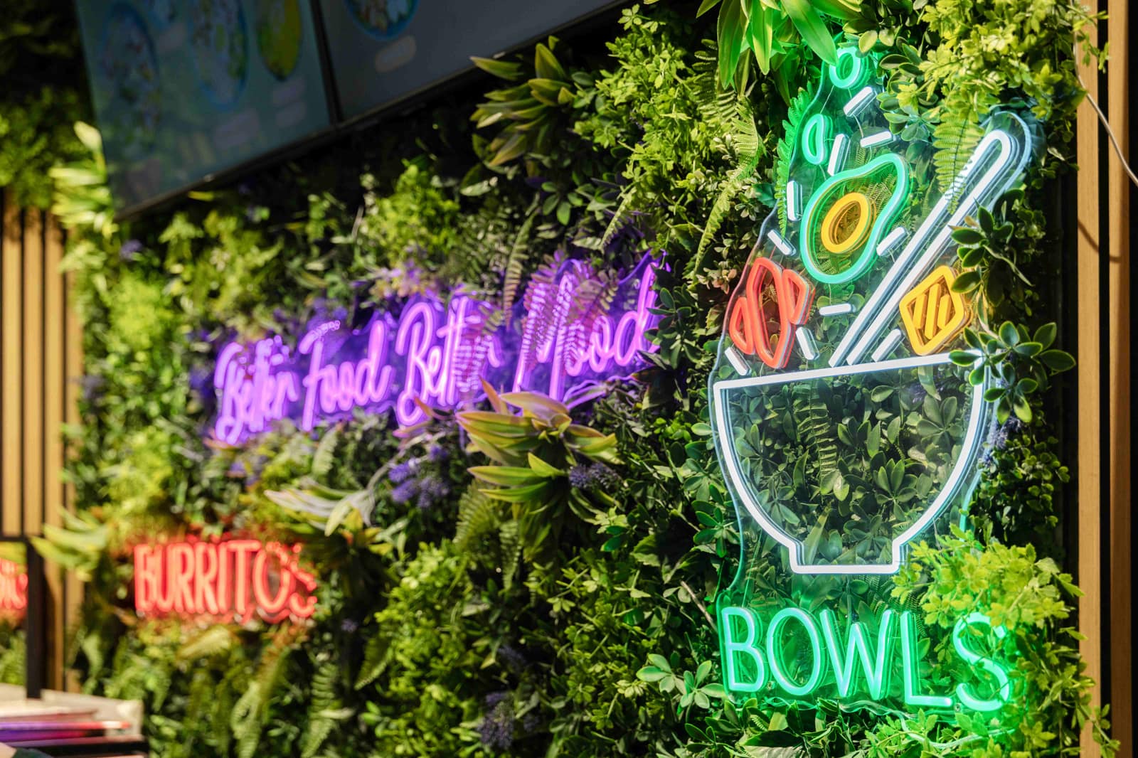 Neon-Schriftzüge an einer begrünten Wand im Food-Court des FORUM Schwanthalerhöhe